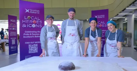 bakers standing next to a large empire biscuit