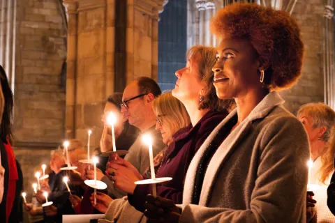 Row of people in church at a carol concert holding candles