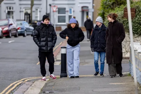 Four young people walking along a residential street